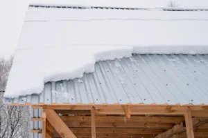 snow sliding down from a wood building with silver metal roofing
